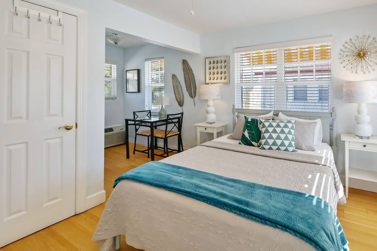 A bedroom with a bed, bedside tables, a desk, and chairs.