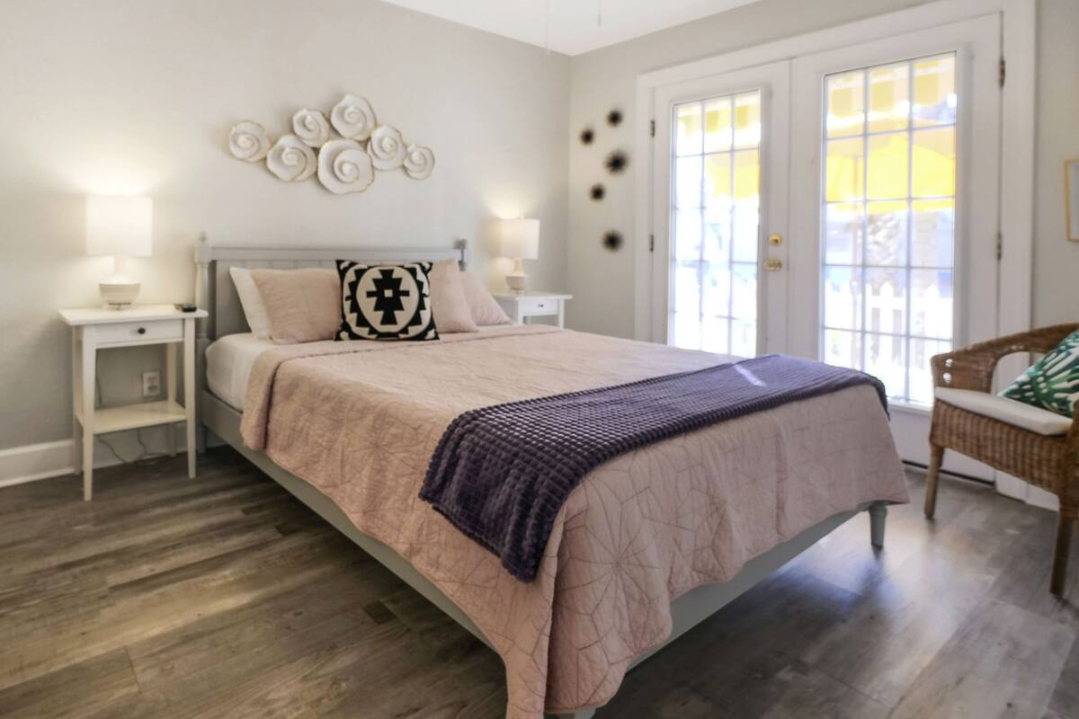 A bedroom with a bed, nightstands, a chair, and a decorative wall piece.