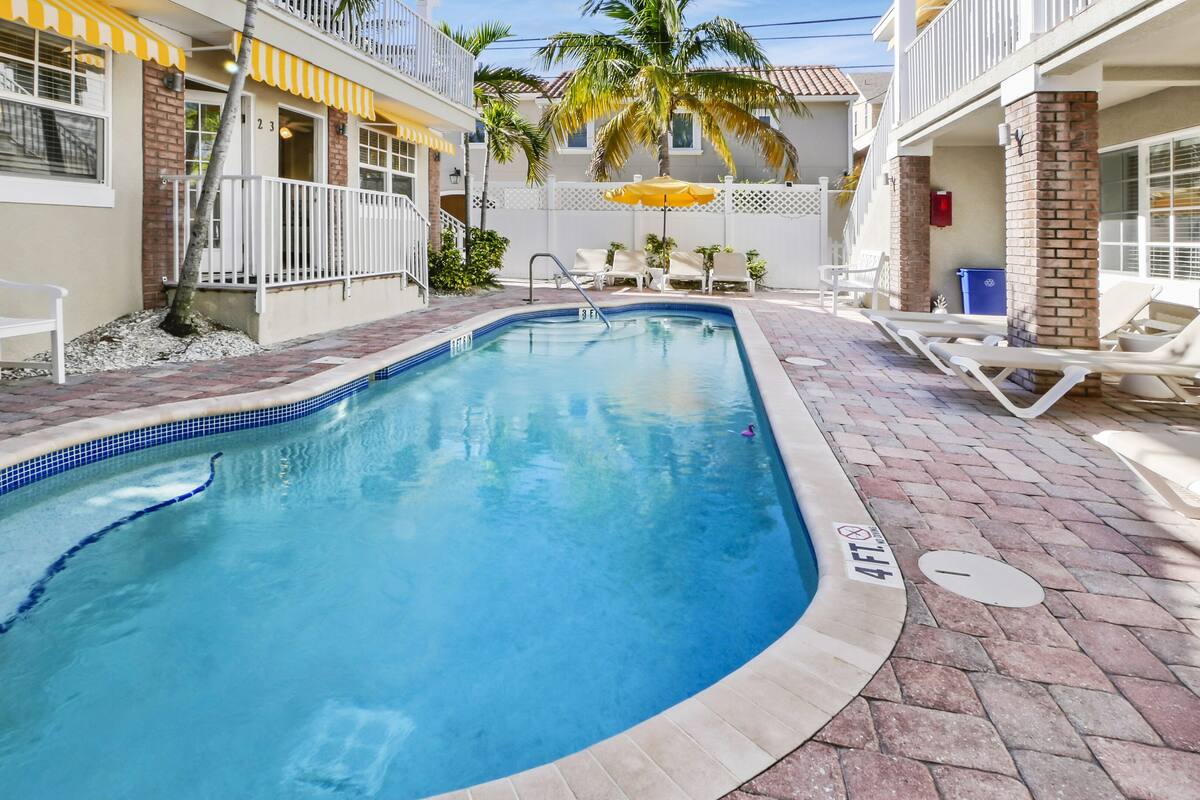 A swimming pool with lounge chairs and a palm tree.