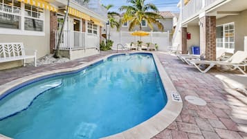 Una piscina al aire libre, sombrillas, sillones reclinables de piscina