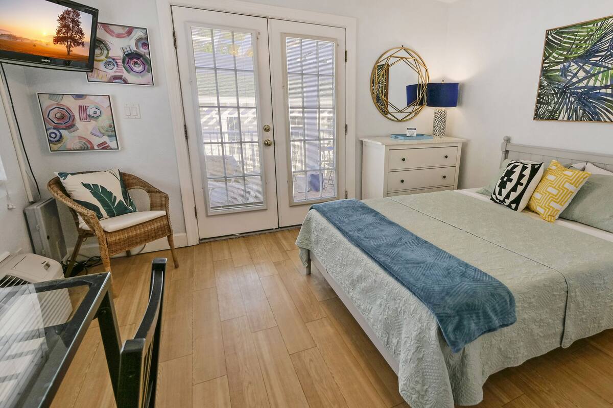 A bedroom with a bed, a chair, a dresser, and a TV.