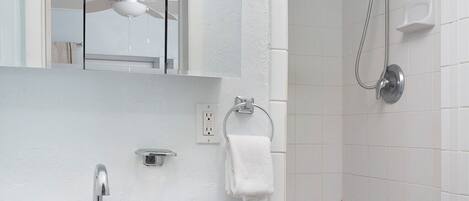 A bathroom with a white sink, a mirror, a ceiling fan, and a shower area.