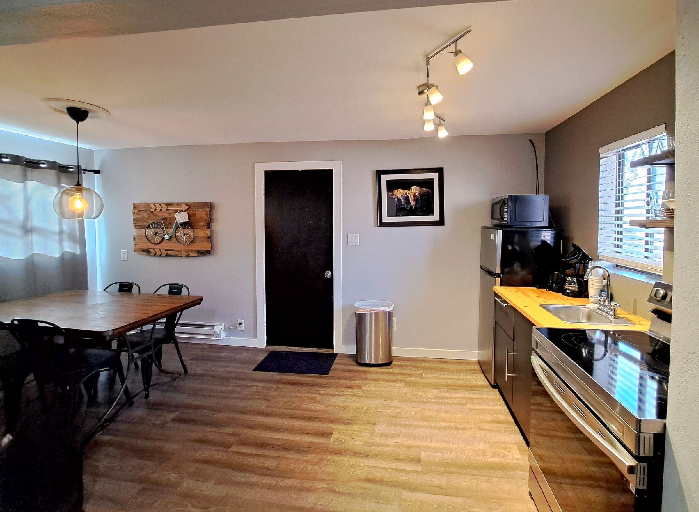 A modern kitchen with a wooden countertop, stainless steel appliances, and a dining area with a wooden table and chairs.