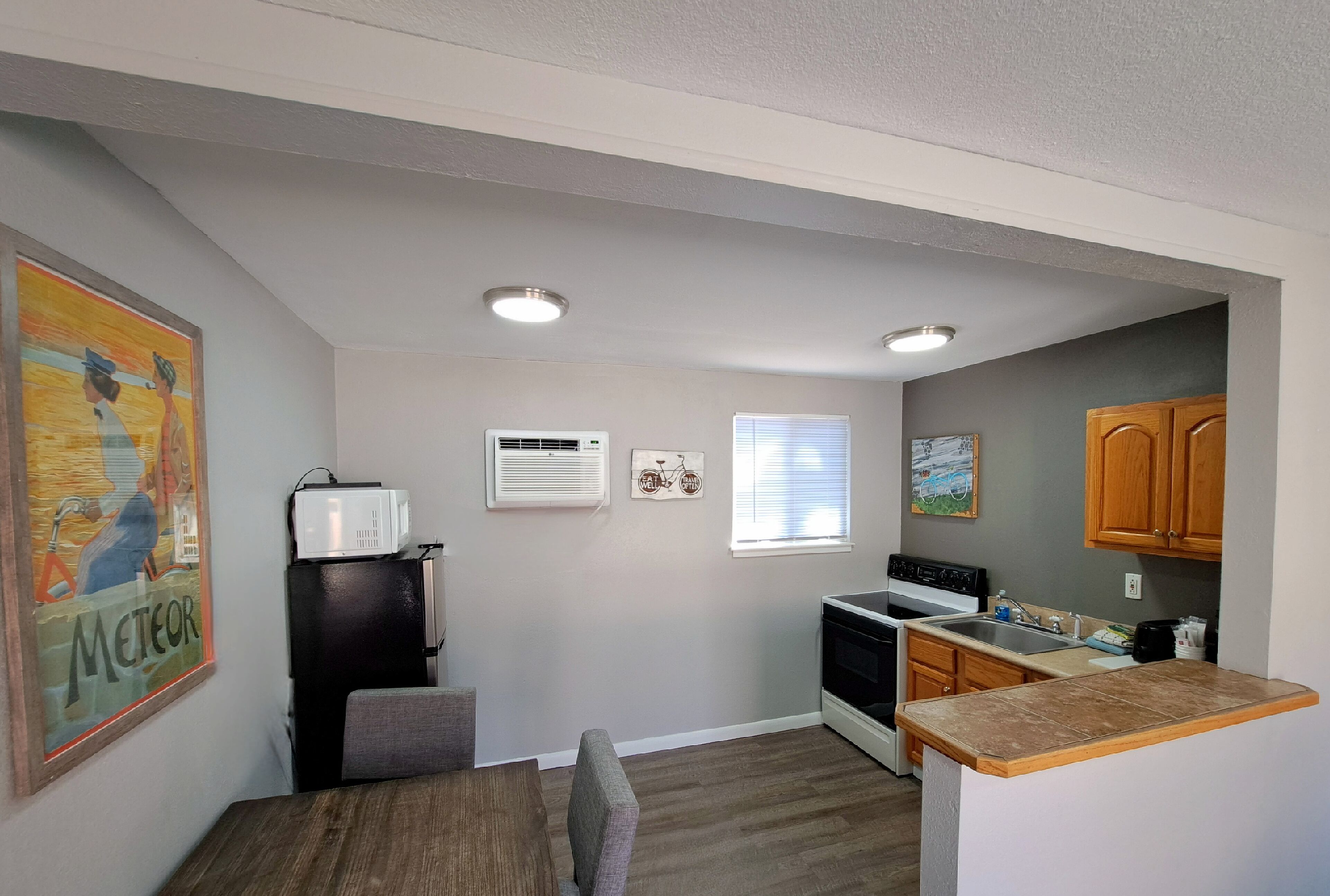 A compact kitchen with a dining area, featuring a refrigerator, microwave, stove, and a small sink.