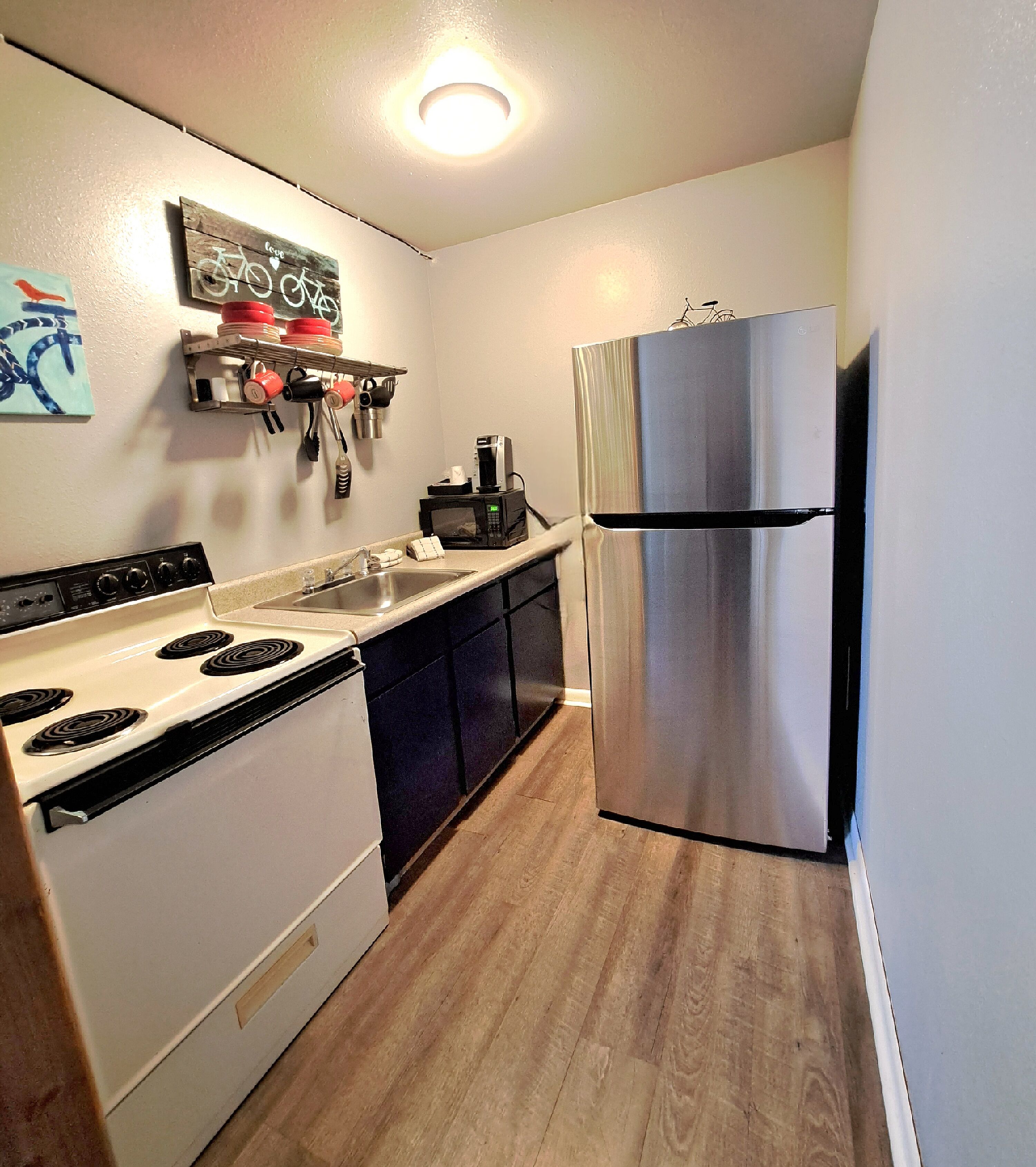 A compact kitchen with a stove, sink, and stainless steel refrigerator.
