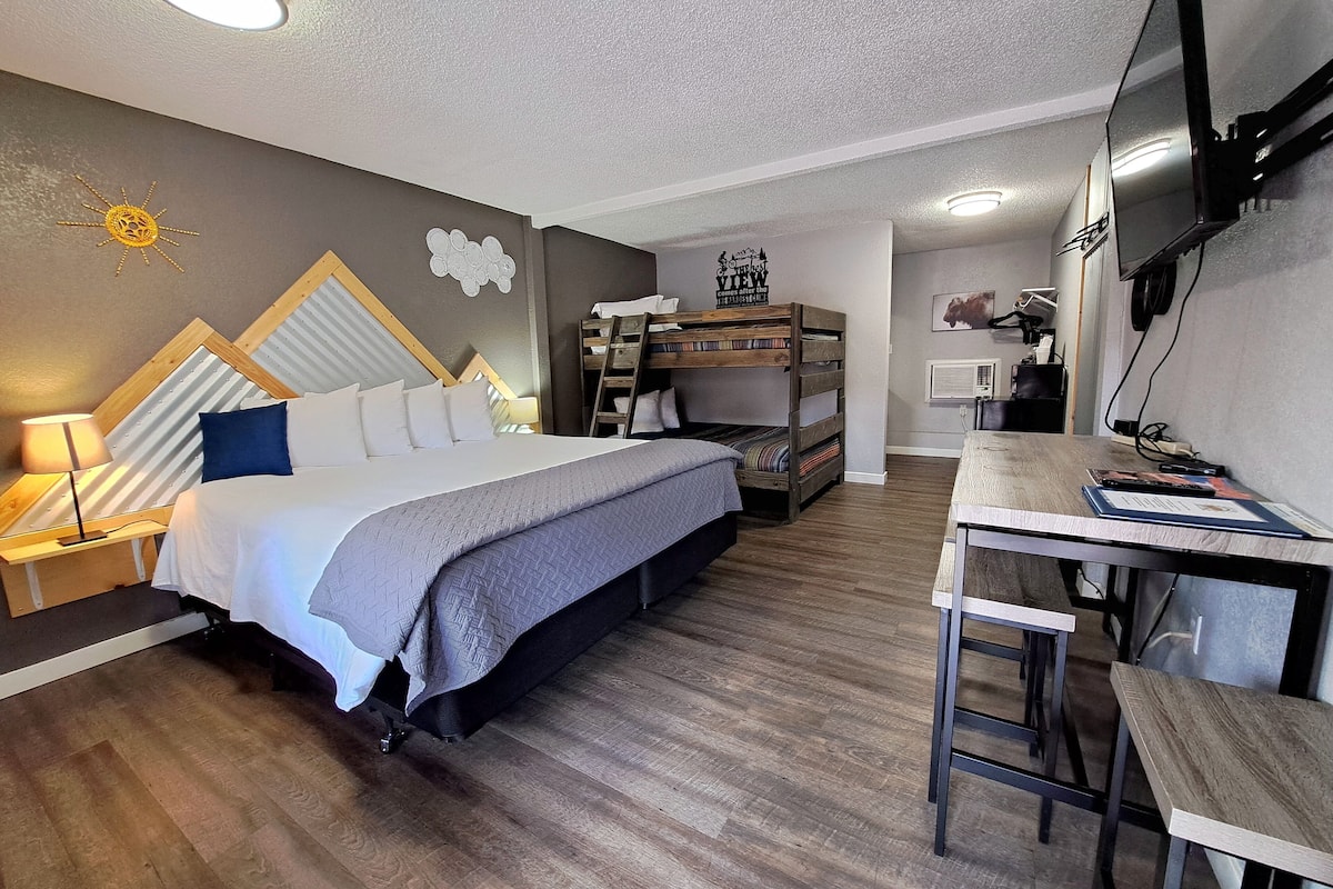A bedroom with a bunk bed, a desk, and a TV.