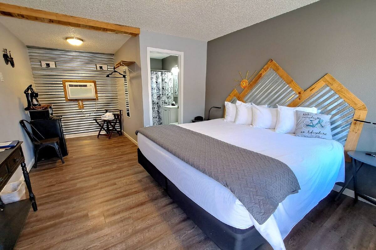 A bedroom with a large bed, wooden headboard, and a view of a balcony.