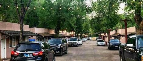 Calle arbolada con coches aparcados y edificios a ambos lados.
