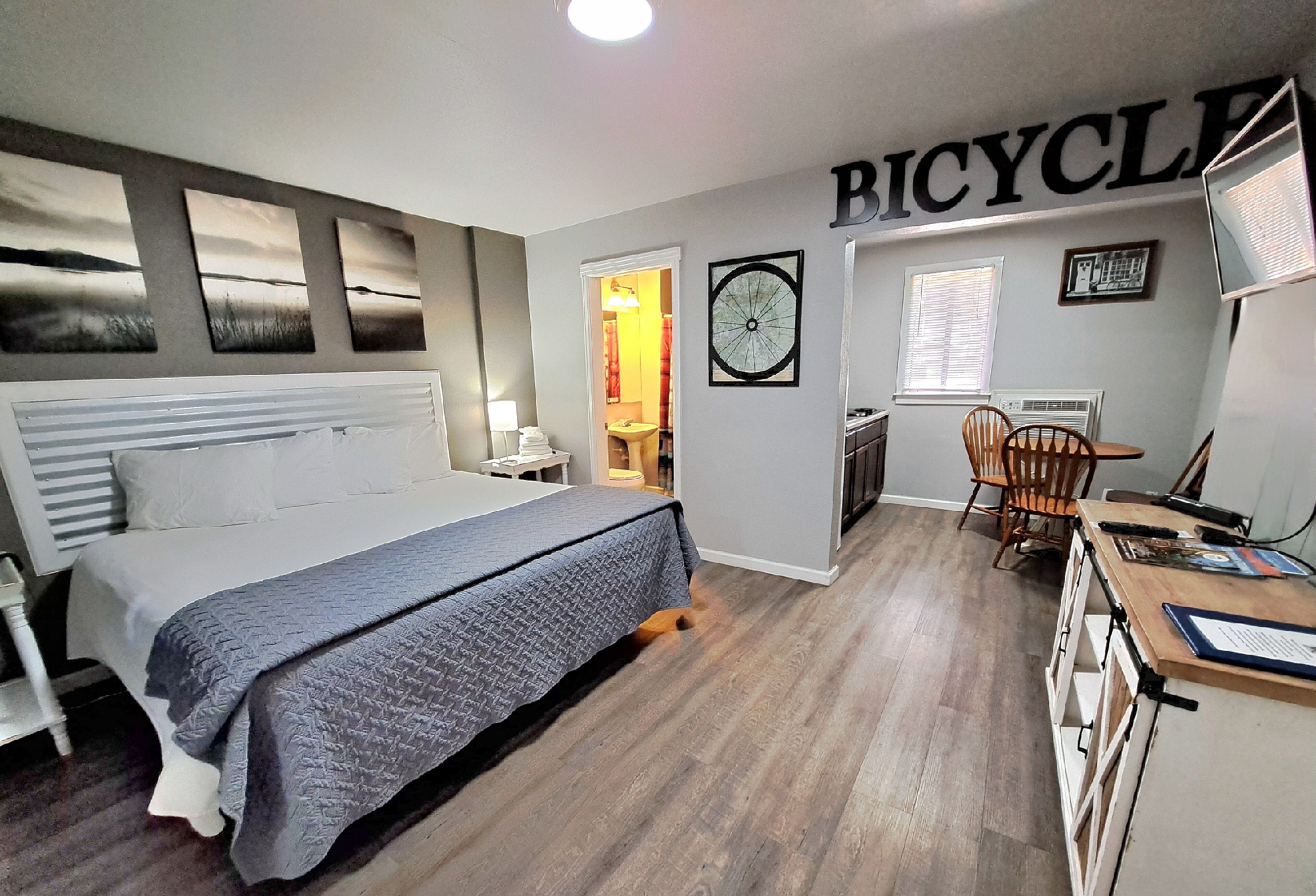 A bedroom with a bed, a desk, and a bicycle-themed wall.