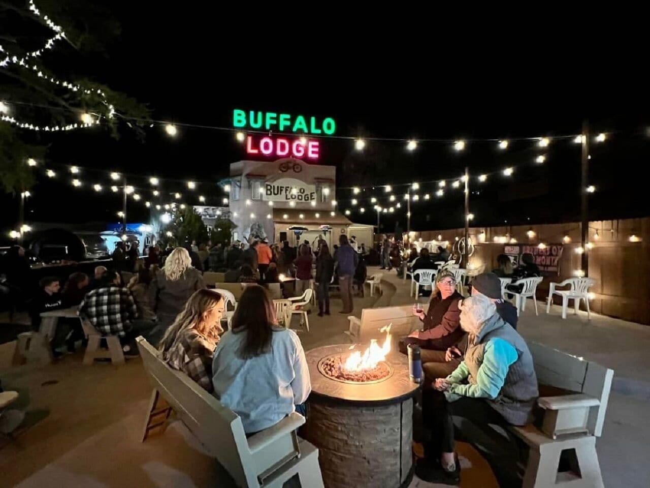 Un área de estar al aire libre en Buffalo Lodge con un brasero y luces colgantes.