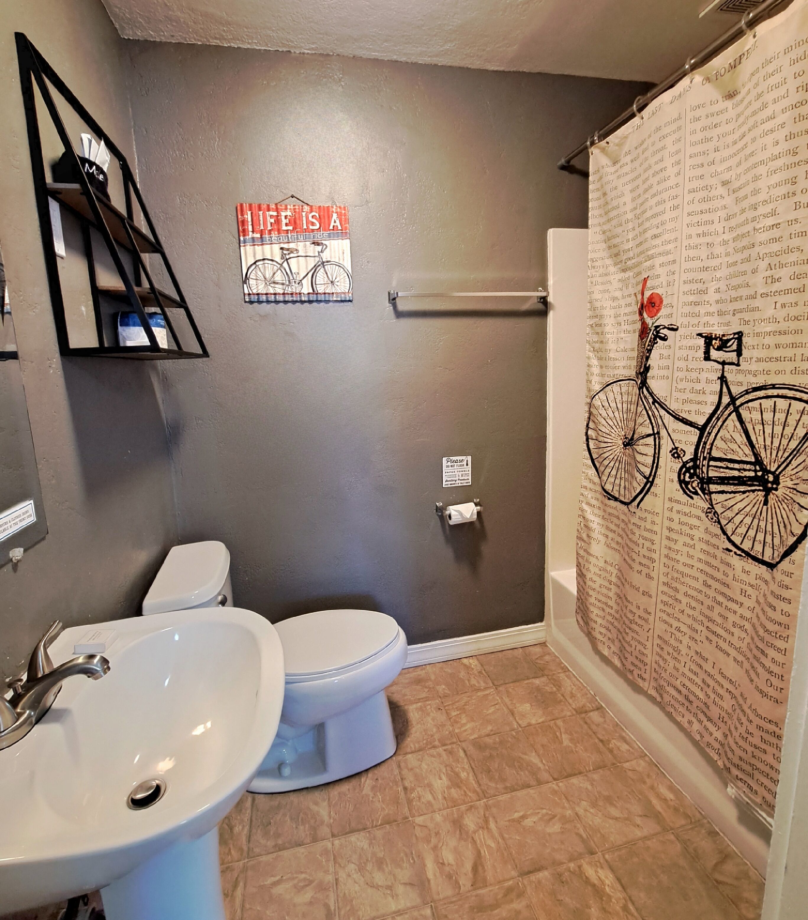 Ein Badezimmer mit Toilette, Waschbecken und Duschvorhang mit Fahrradmotiv.