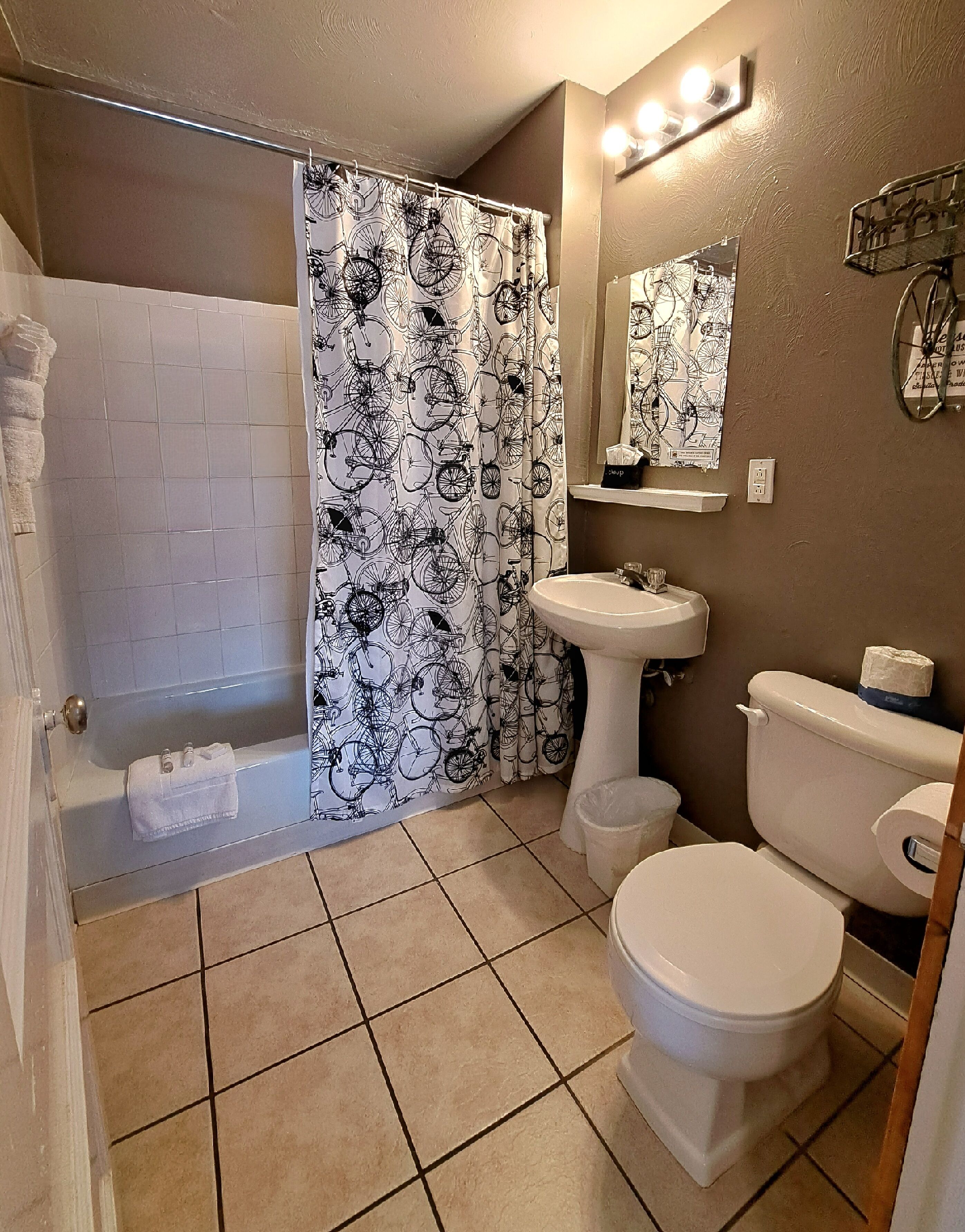 Une salle de bain équipée d’une baignoire, de toilettes, d’un lavabo et d’un rideau de douche orné d’un motif de vélos.