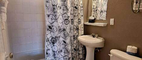 A bathroom with a bathtub, toilet, sink, and shower curtain with a bicycle pattern.