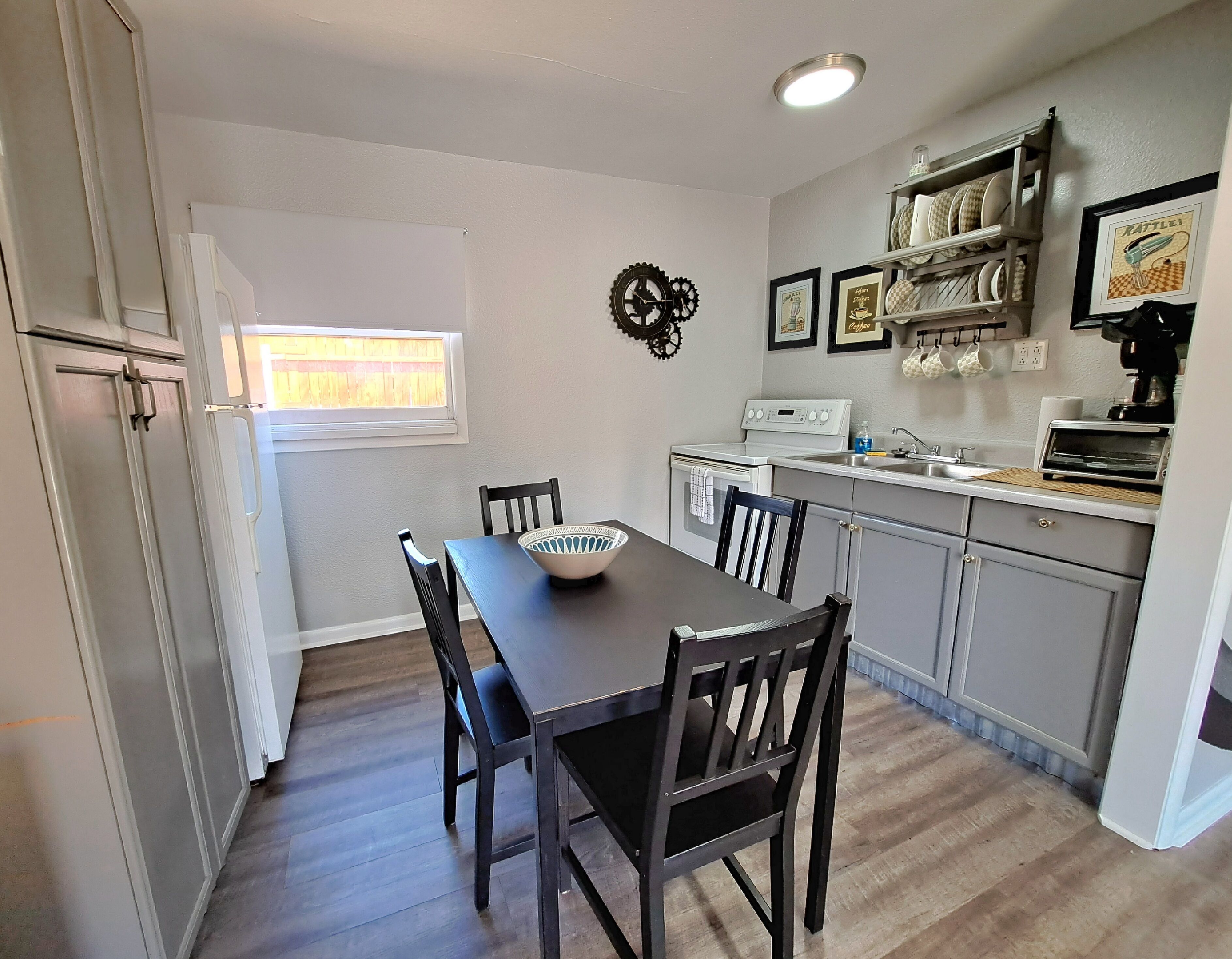 Une cuisine de taille réduite comprenant une table à manger, des chaises, une cuisinière et une machine à café.