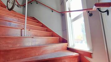 A staircase with wooden steps and a handrail, leading to a landing with a window and a bicycle rack.