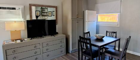 Een kleine keuken met een eethoek, een ingebouwde televisie en een koelkast.