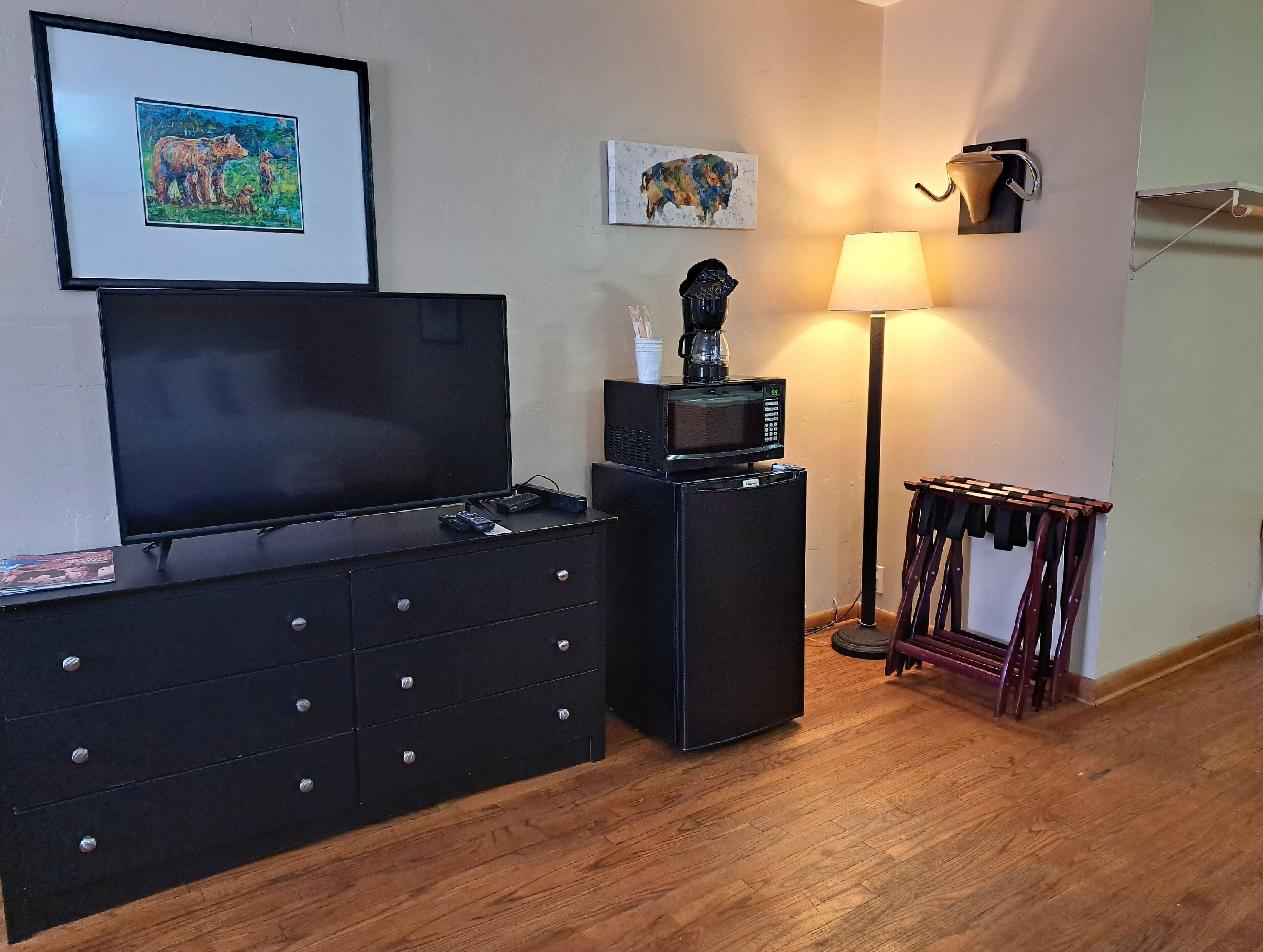 Ein Wohnzimmer mit Fernseher, Kaffeemaschine, Mikrowelle und Lampe.
