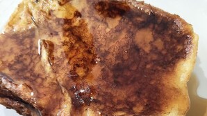 A piece of French toast with syrup on a white plate. - Micro Hotel Condo Suites (Santo Domingo)