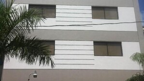 A multi-story building with a flat roof, large windows, and a gated entrance. - Micro Hotel Condo Suites (Santo Domingo)