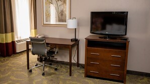 Hotellihuone, jossa on työpöytä, tuoli, televisio, lamppu ja puhelin.
