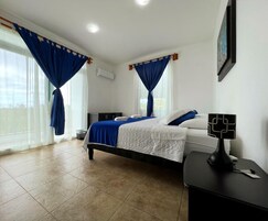 Un dormitorio con cama, cortinas, una mesita de noche y aire acondicionado instalado en la pared.