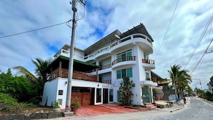 A multi-story building with a white facade, balconies, and a sign that reads "CALLY". - Hotel Cally Galapagos (Puerto Villamil)