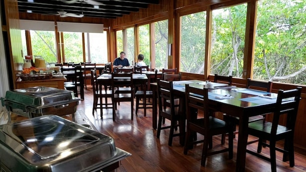 A restaurant with wooden floors, large windows, and buffet service. - Hotel Cally Galapagos (Puerto Villamil)