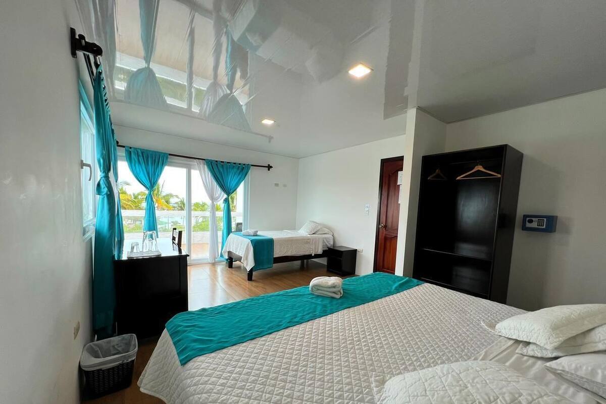 A hotel room with a large bed, a wardrobe, a desk, and a window with curtains.