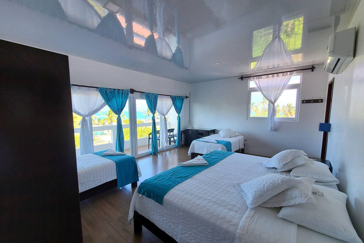 A hotel room with two beds, a desk, and a view of the ocean.