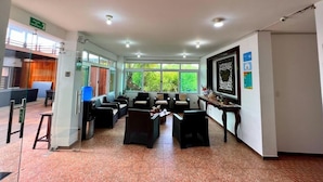 A spacious lobby with a seating area, a reception desk, and a view of the outdoors. - Hotel Cally Galapagos (Puerto Villamil)