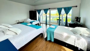 A hotel room with two beds, a desk, a chair, and a large window with curtains. - Hotel Cally Galapagos (Puerto Villamil)
