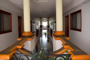 Un largo pasillo con columnas y puertas a ambos lados.