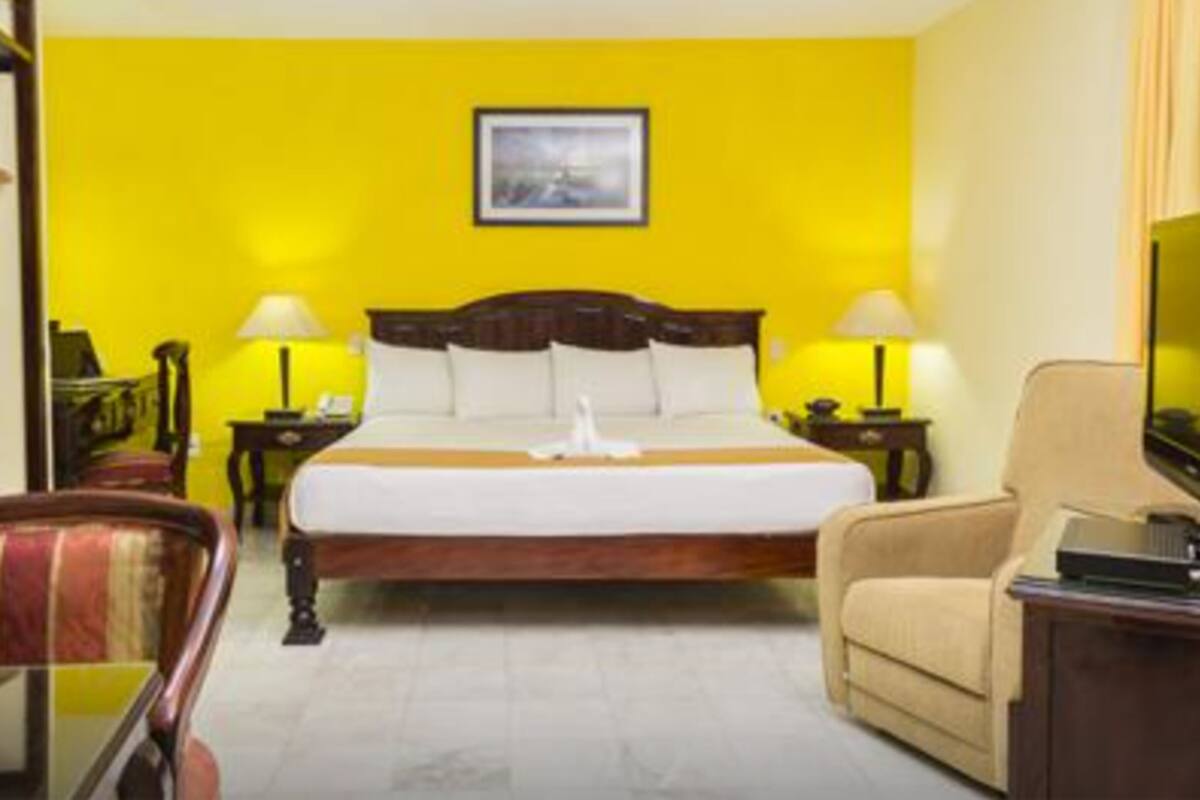 A hotel room with a large bed, two bedside tables with lamps, a chair, and a television.
