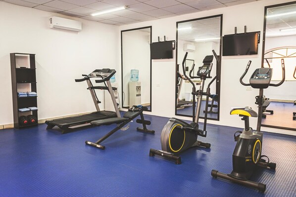 Uma academia com equipamentos de ginástica, incluindo esteiras, elíptico e bicicleta ergométrica.