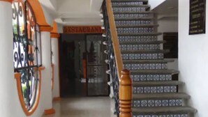 Una escalera con balustradas de madera y azulejos decorativos que lleva a un restaurante.