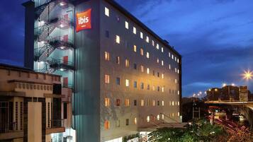 A modern hotel with a prominent 'ibis Hotels' sign, multiple floors, and a staircase on the left.