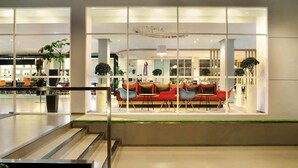 A modern lobby with a central seating area, glass partitions, and indoor plants. - Ibis Bandung Pasteur (Bandung)