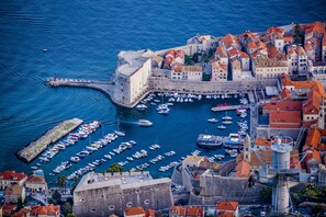 A historic coastal town with a fortified castle, a marina with numerous boats, and traditional red-roofed buildings. - SUNce Palace Apartments with free offsite parking (Dubrovnik)