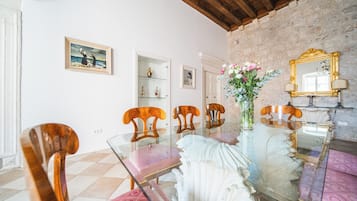 A dining area with a glass table, wooden chairs, and a vase of flowers.