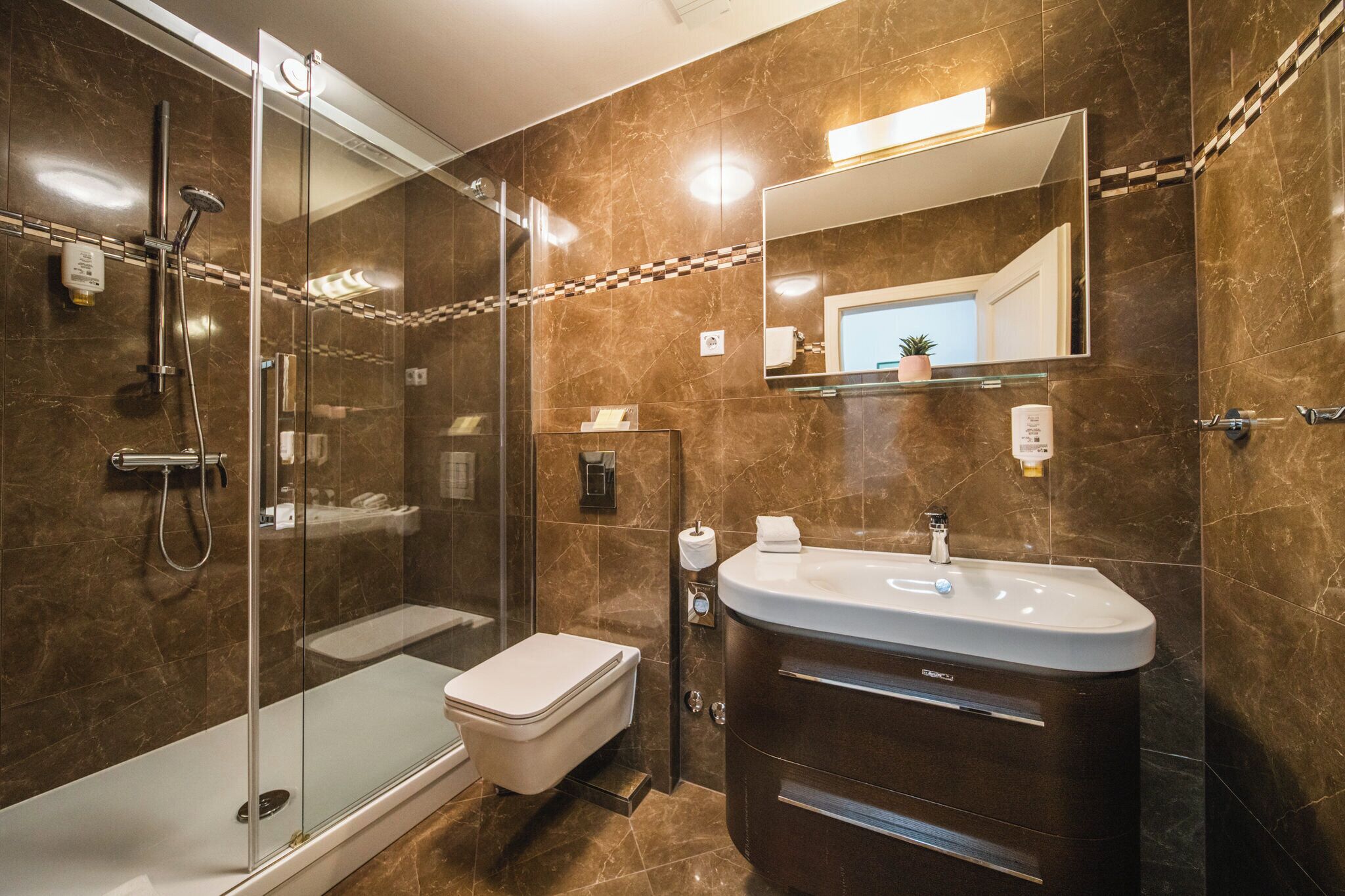 A modern bathroom with a glass-enclosed shower, a white toilet, and a vanity with a sink.
