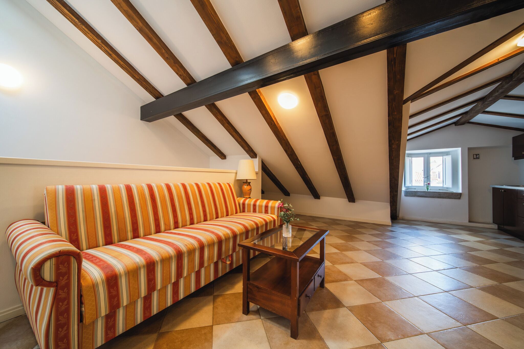 A cozy living room with a striped sofa, a wooden coffee table, and a checkered floor.