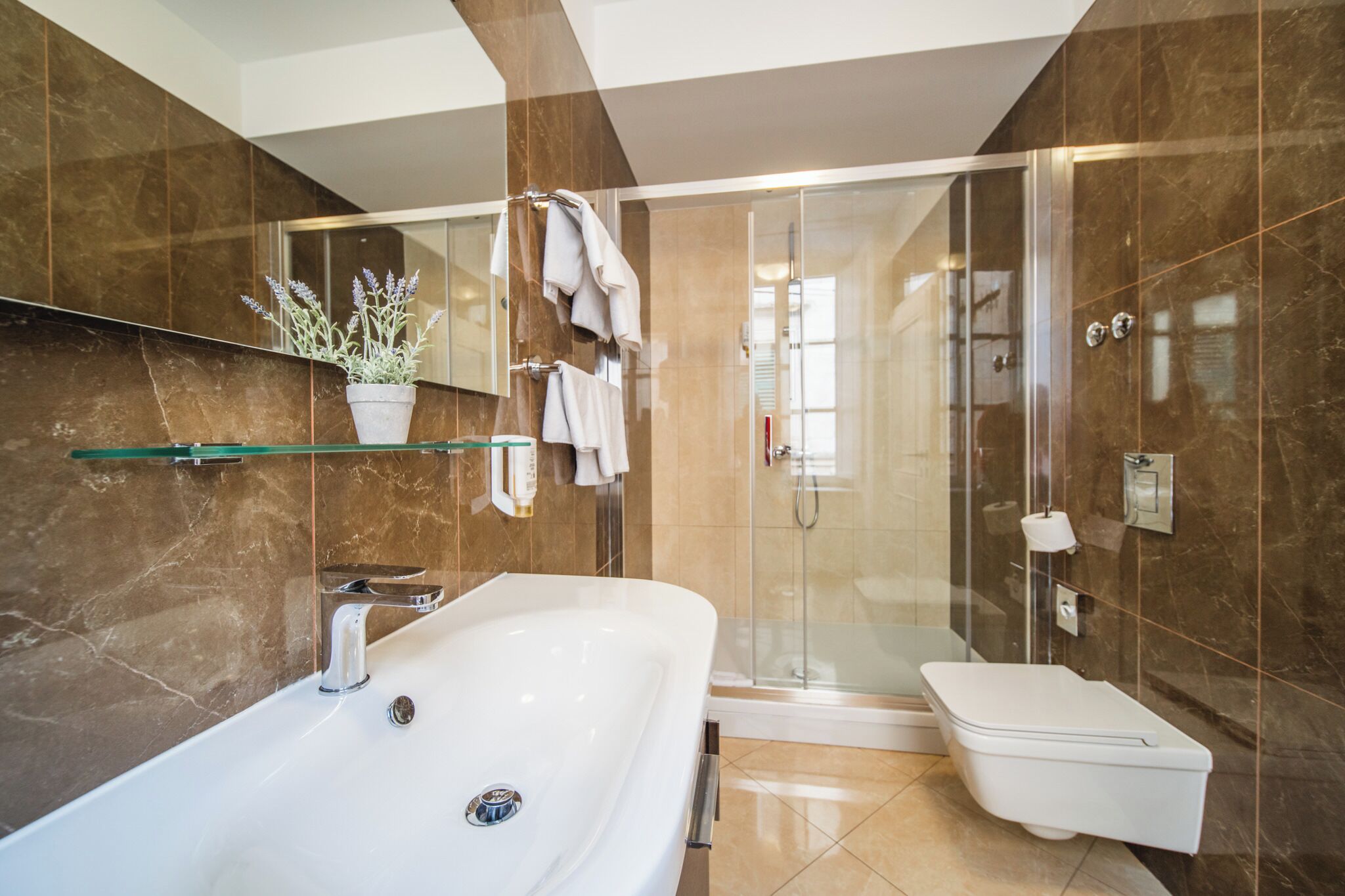 Une salle de bain moderne avec une douche à parois de verre, une baignoire blanche et un grand lavabo.