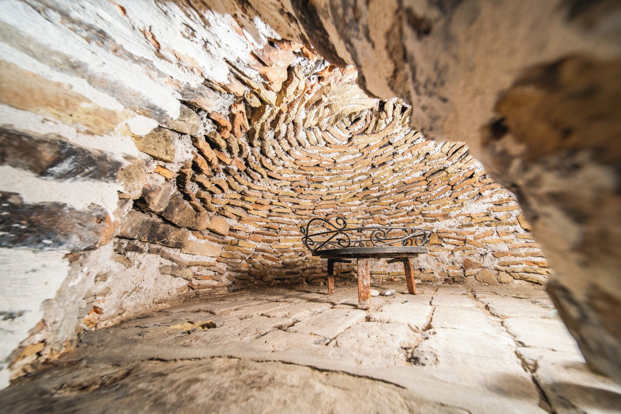 A stone-walled room with a bench.