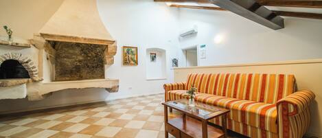 Una sala de estar con piso a cuadros, un sofá, una mesa de centro y una chimenea.