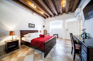 A bedroom with a wooden bed, a nightstand, a chair, a desk, and a window with a view.