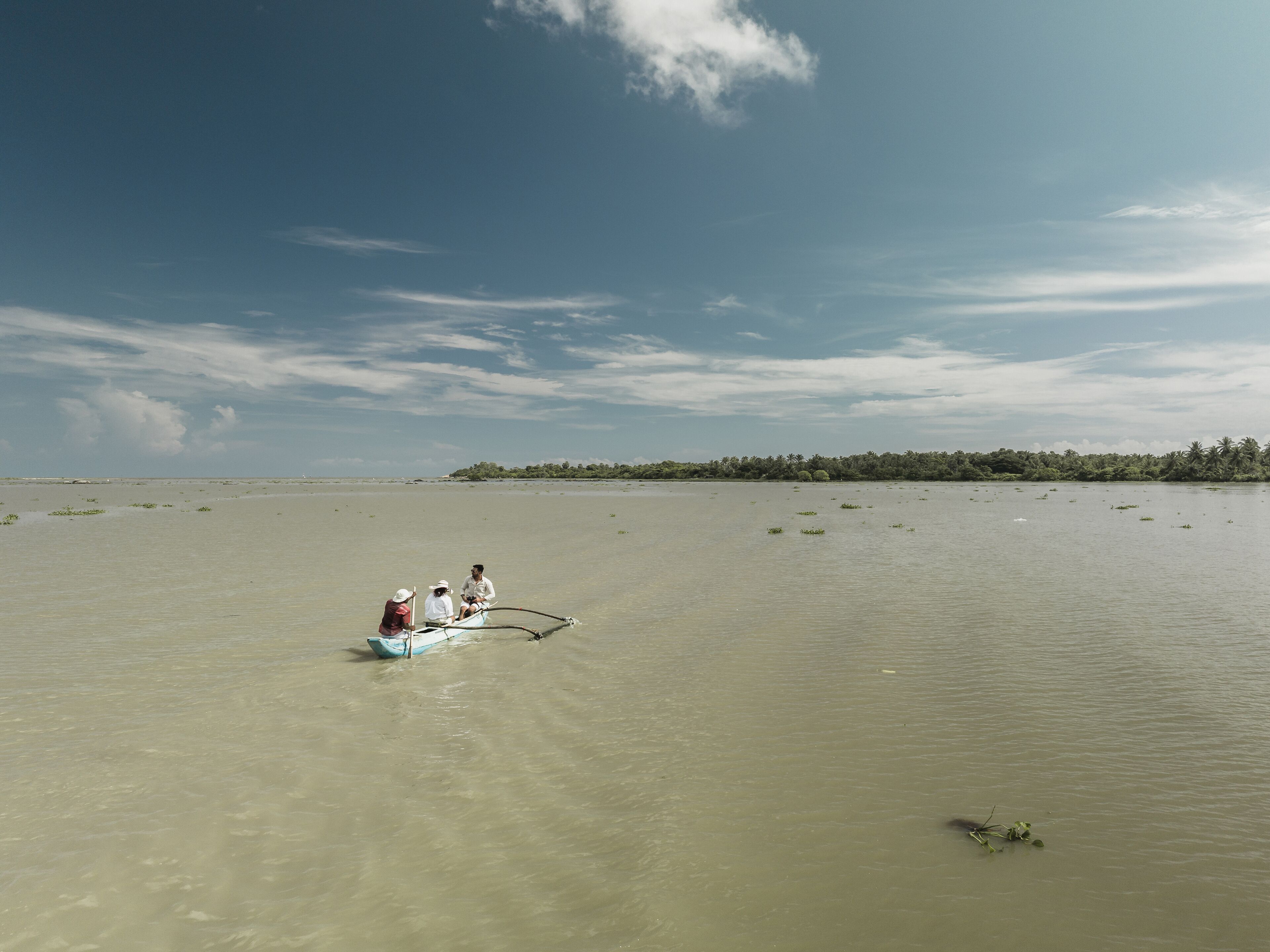 A calm body of water with a small boat carrying three people.