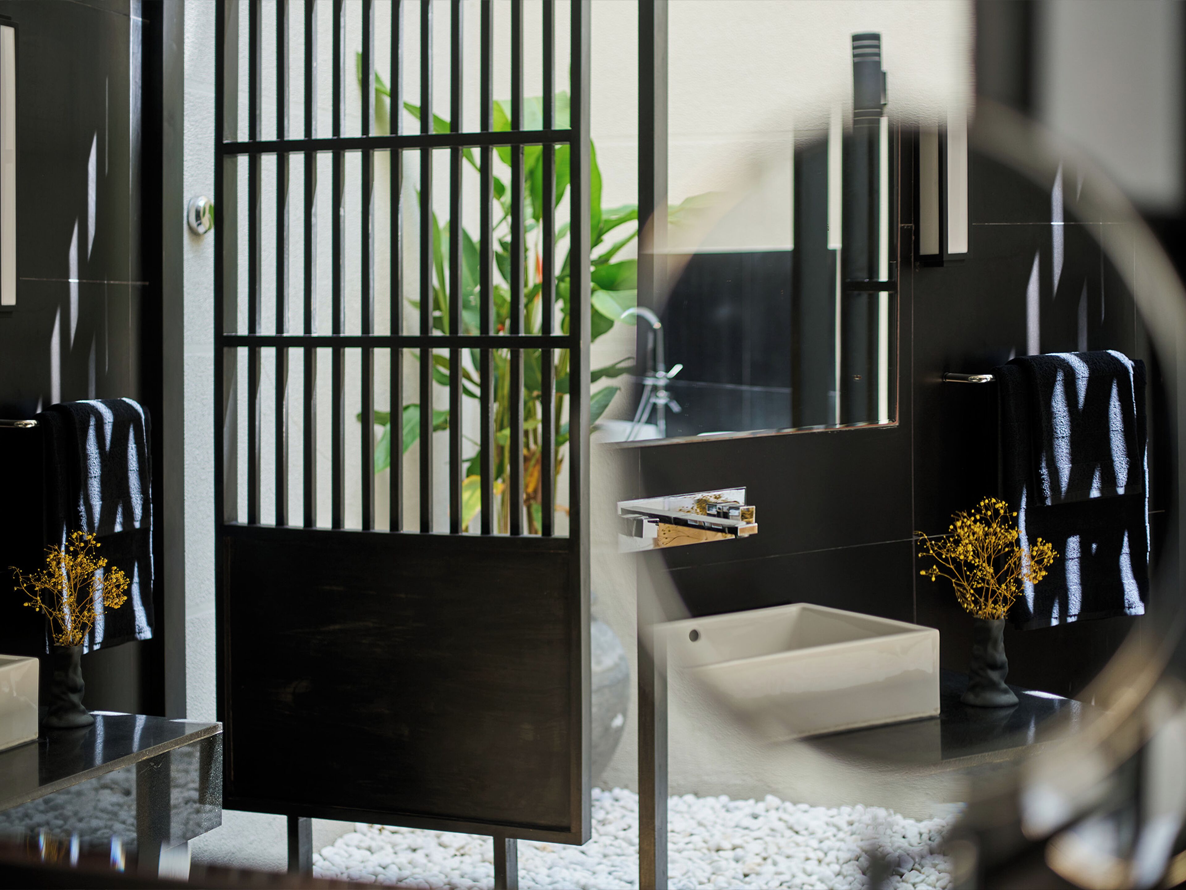 Een moderne badkamer met een zwart wastafelmeubel, een witte wasbak en een spiegel.