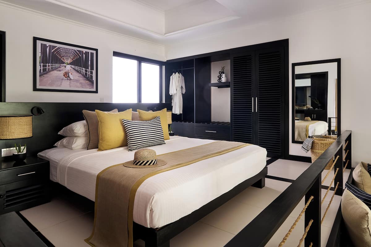 A modern bedroom with a large bed, a wardrobe, and a mirror.
