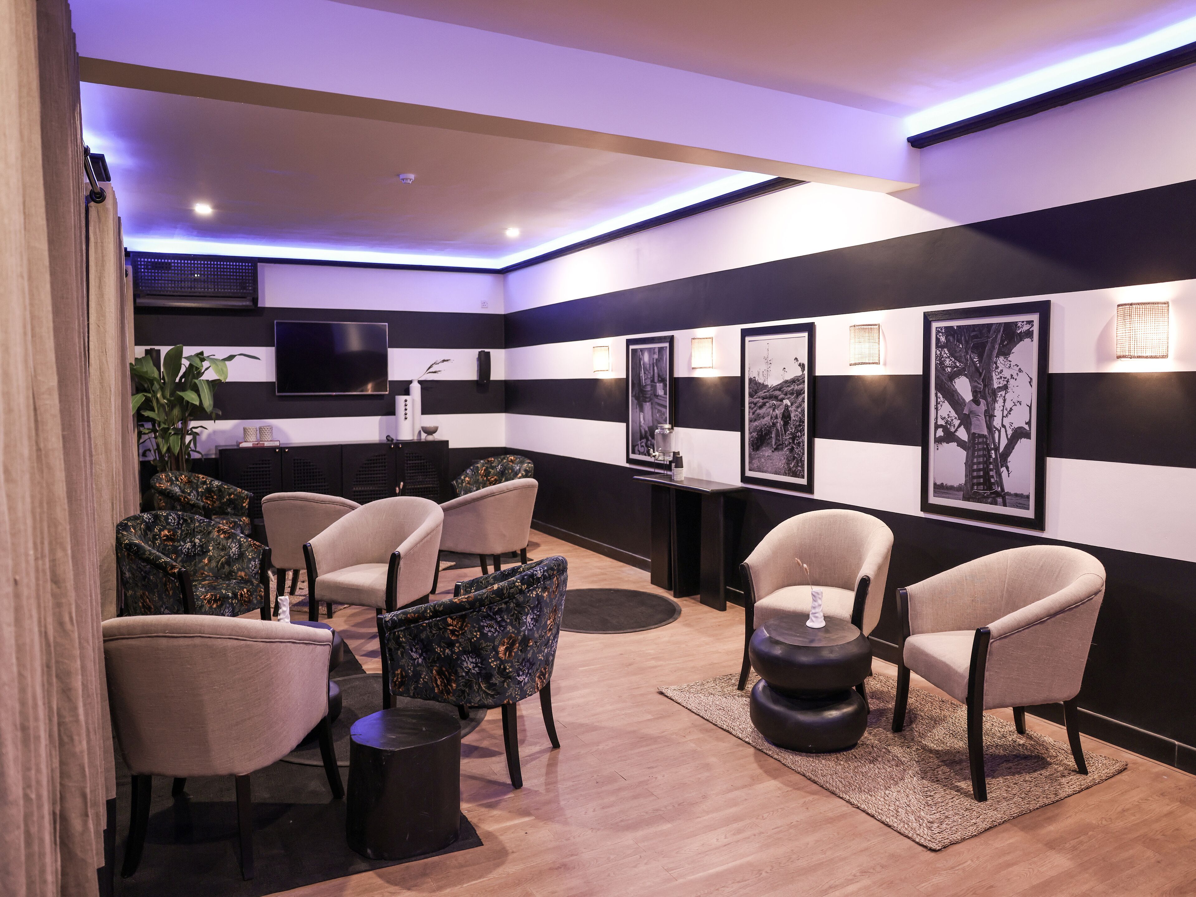 Un espacio lounge moderno con paredes a rayas, diversas opciones de asiento y obras de arte enmarcadas.
