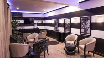 Un espacio lounge moderno con paredes a rayas, diversas opciones de asiento y obras de arte enmarcadas.